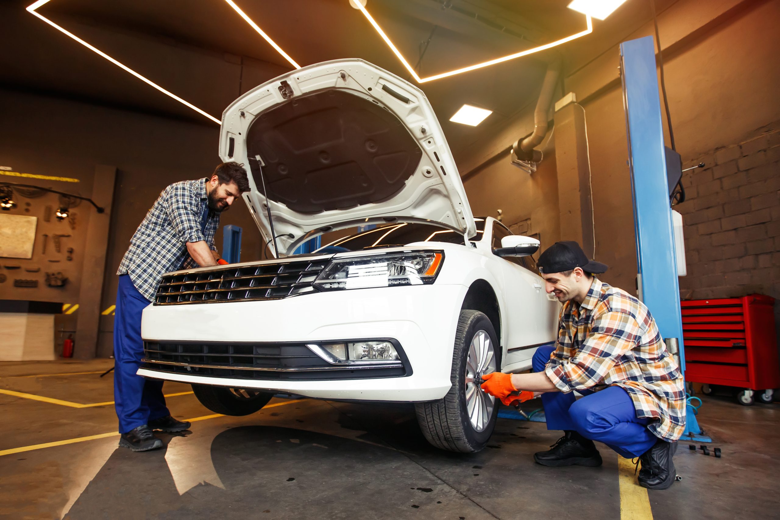 smiling mechanics repairing modern car in workshop smiling mechanics repairing modern car in workshop
